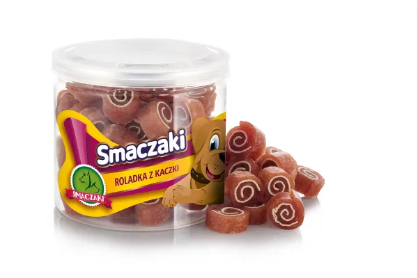 Przezroczysty słoik z żółtą etykietą marki stoi na białym tle, a obok niego piętrzą się różowobrązowe plasterki ze spiralnym rysunkiem na przekroju.